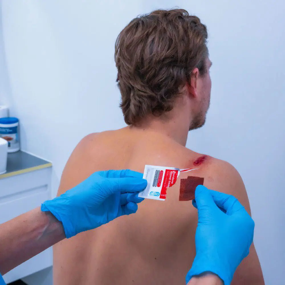 First responder applying iodine swab to patient's back prior to injection