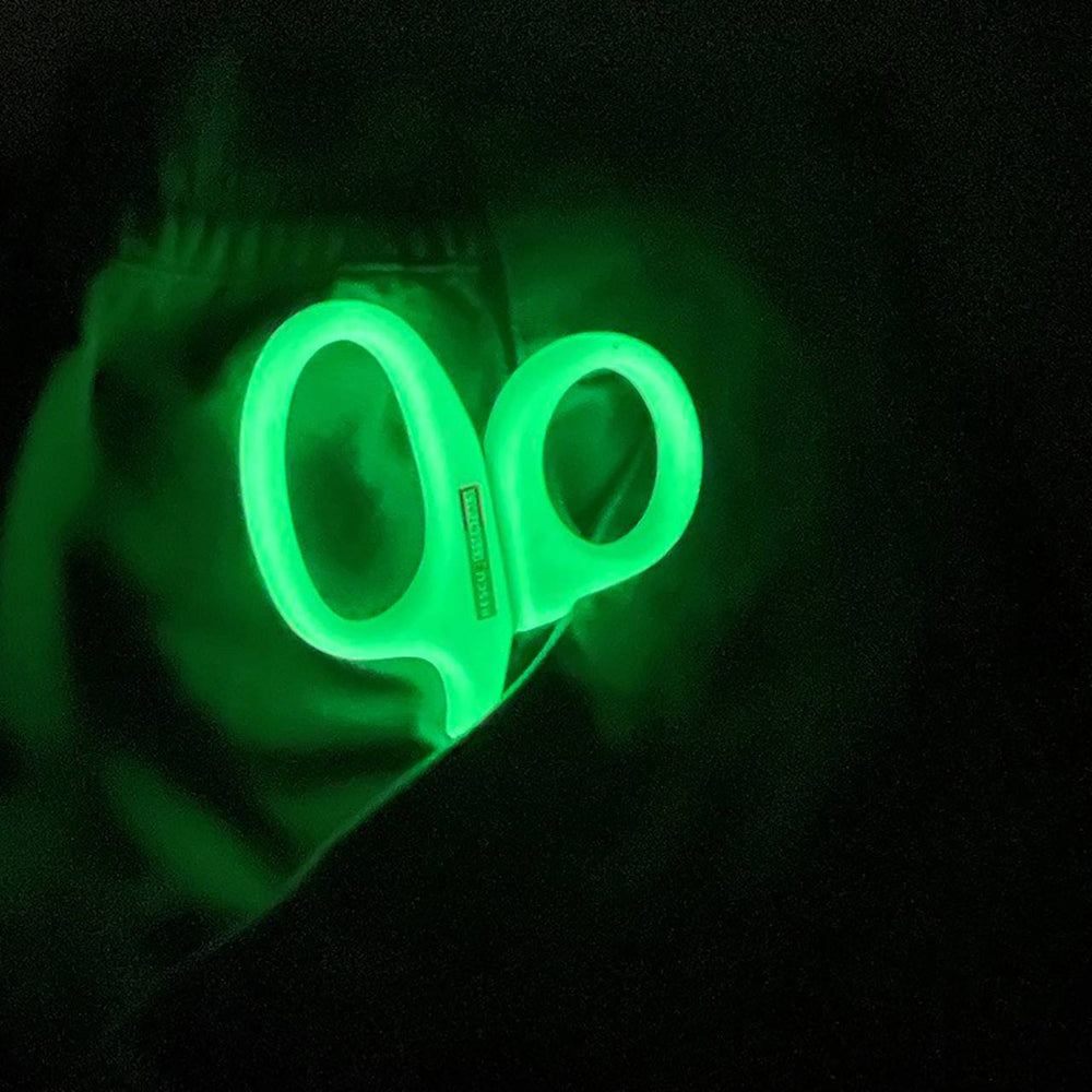 Glow-in-the-dark shears illuminated in the dark, emitting a bright green glow.