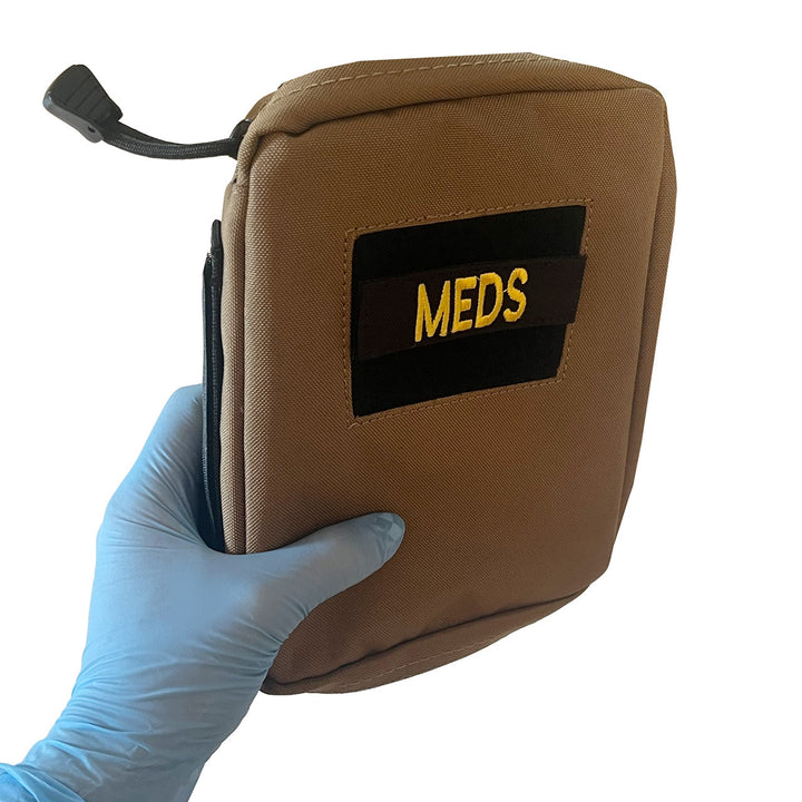 Gloved hand holding the pouch to show compact size and thickness.