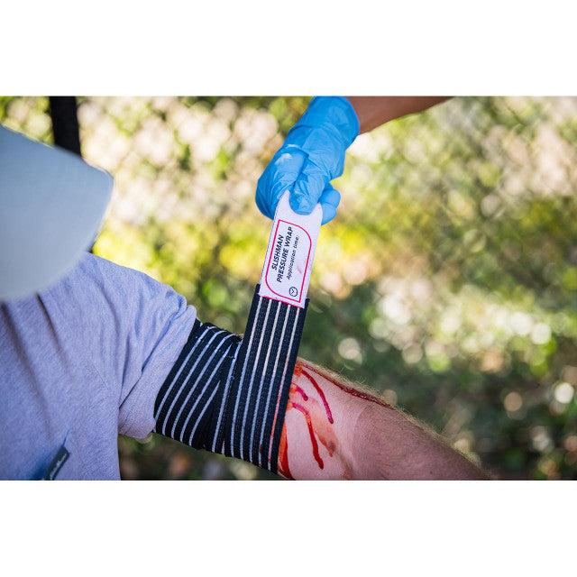 Slishman Pressure Wrap being applied to a simulated leg wound by a gloved responder.