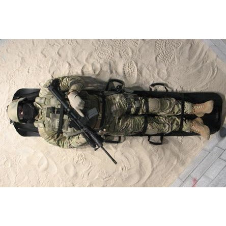 Rescuer carrying a casualty secured in the Foxtrot litter during a tactical operation.