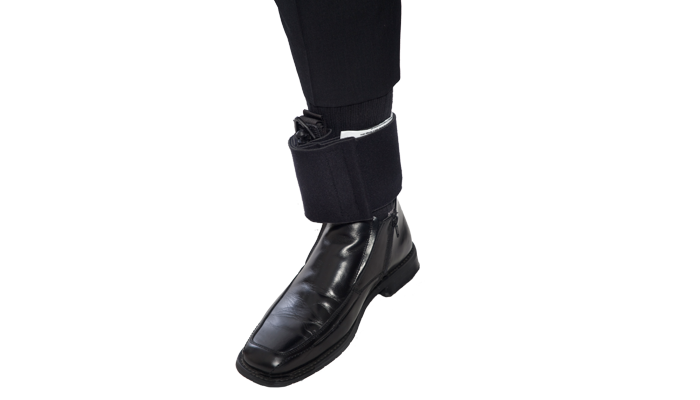 Black ankle medical kit secured around the lower leg above a black tactical boot, worn under pants.