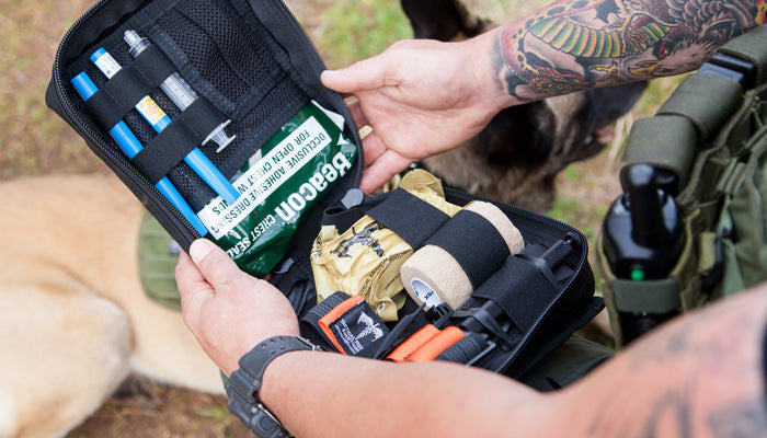Handler opening the K9 trauma kit pouch to access supplies.