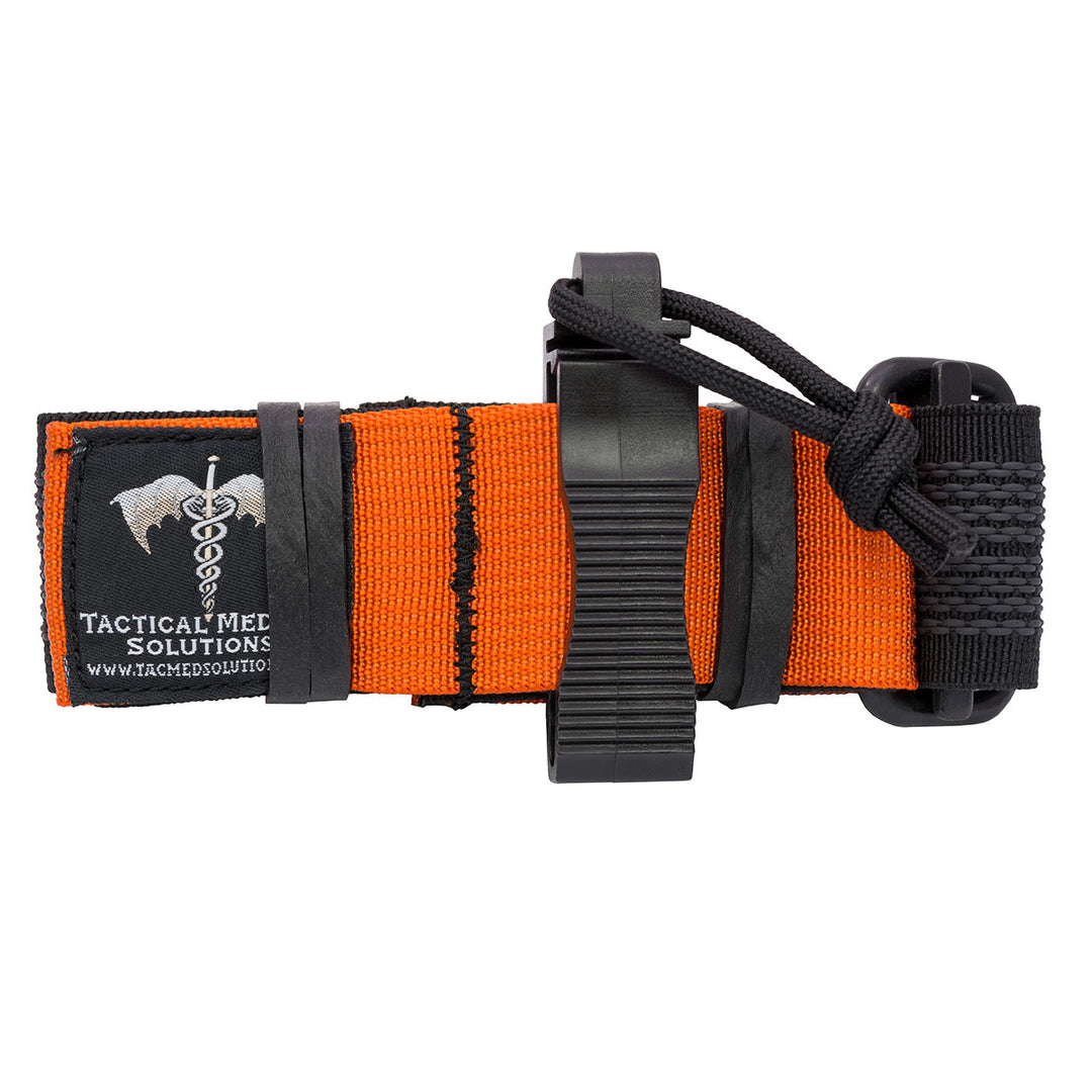 K9 Tourniquet with orange and black webbing, windlass rod, and Tactical Medical Solutions patch displayed on a grey background.