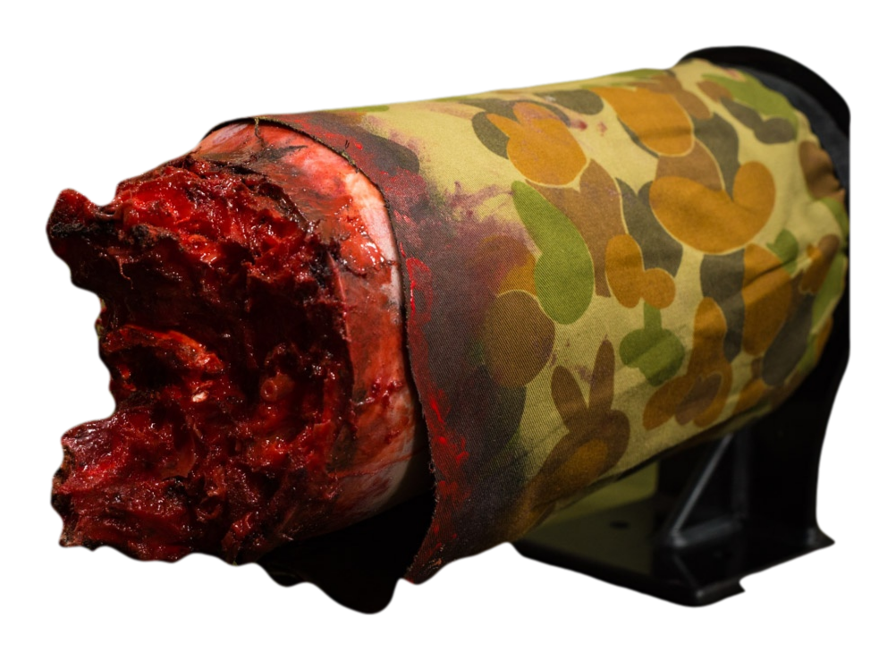 Realistic bleeding leg wound simulator with camo wrap for emergency tourniquet training.