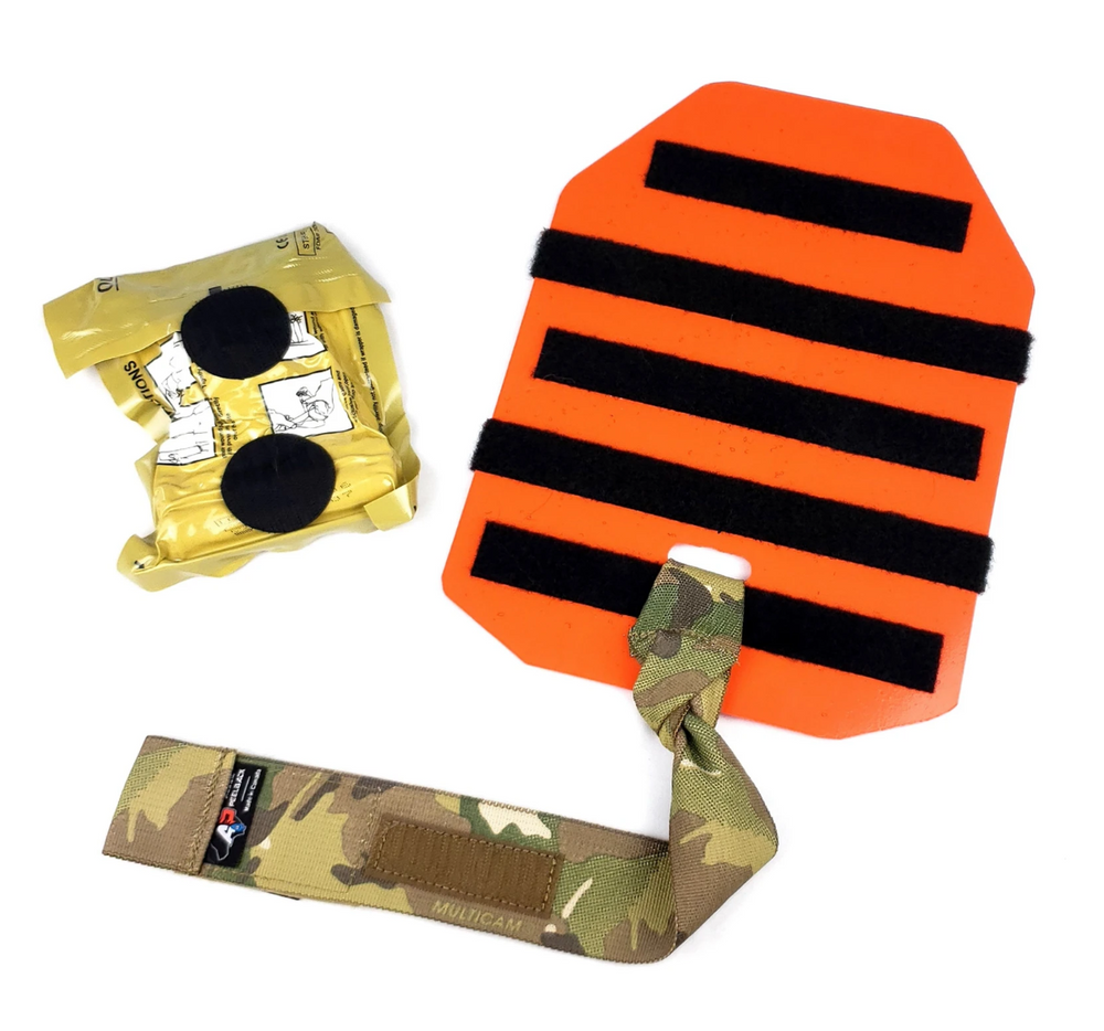 Laid-out components of the Med Plate including orange baseplate, camouflage lanyard, and vacuum-sealed medical gear.