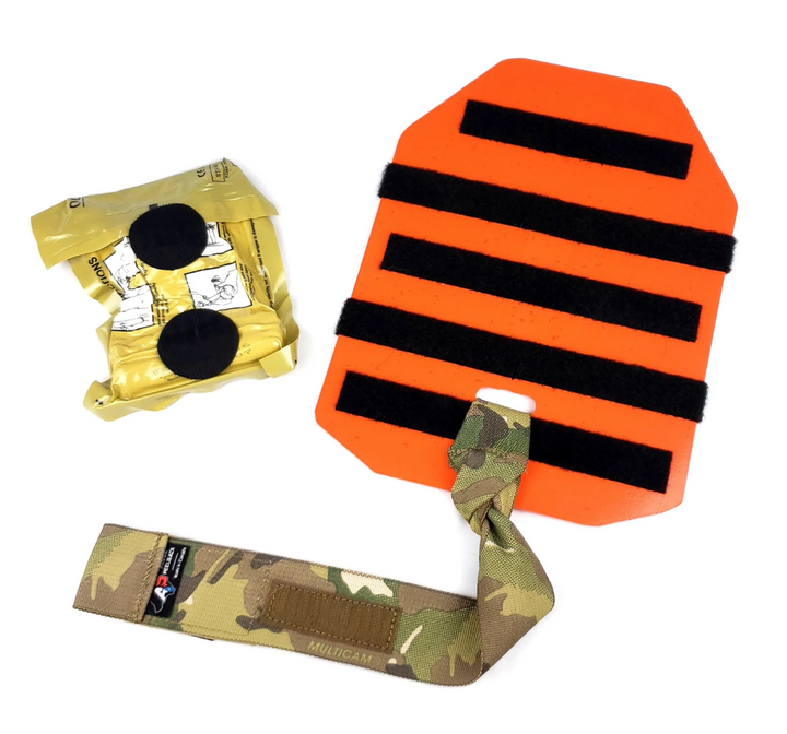 Laid-out components of the Med Plate including orange baseplate, camouflage lanyard, and vacuum-sealed medical gear.