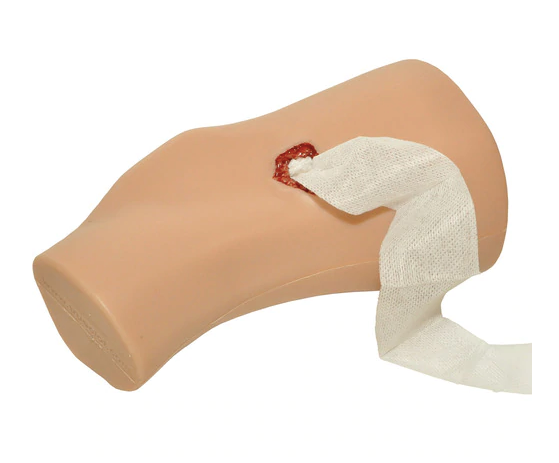 Simulated arm with wound partially packed using gauze, showing side perspective.