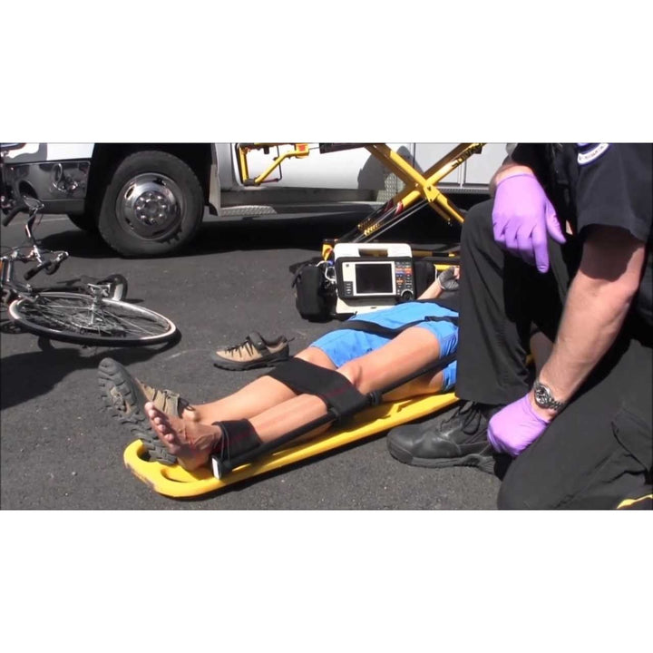 First responder applies the Slishman traction splint to a casualty on a yellow stretcher during a field scenario.