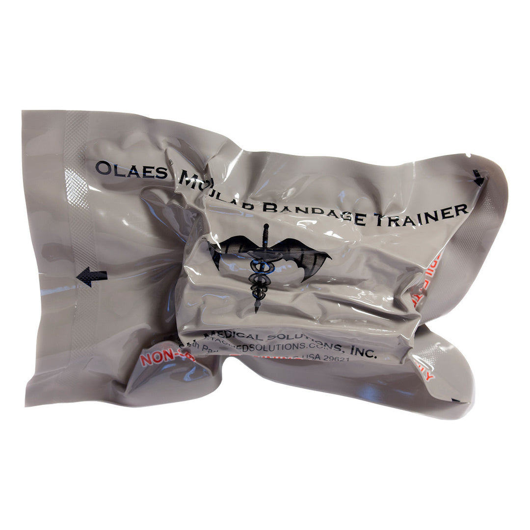 Vacuum-sealed Olaes Modular Bandage Trainer in silver-grey packaging with black medical insignia and instructional arrows.
