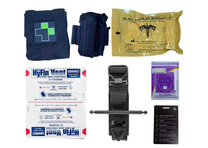 Flat lay of the TacMed Split IFAK contents including a black tourniquet, combat gauze, emergency trauma dressing, gloves, and various first aid supplies arranged beside the open pouches.