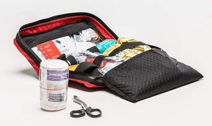 Contents of the TacMed SmartAid kit displayed outside the bag, including gauze, bandages, shears, and antiseptic items.