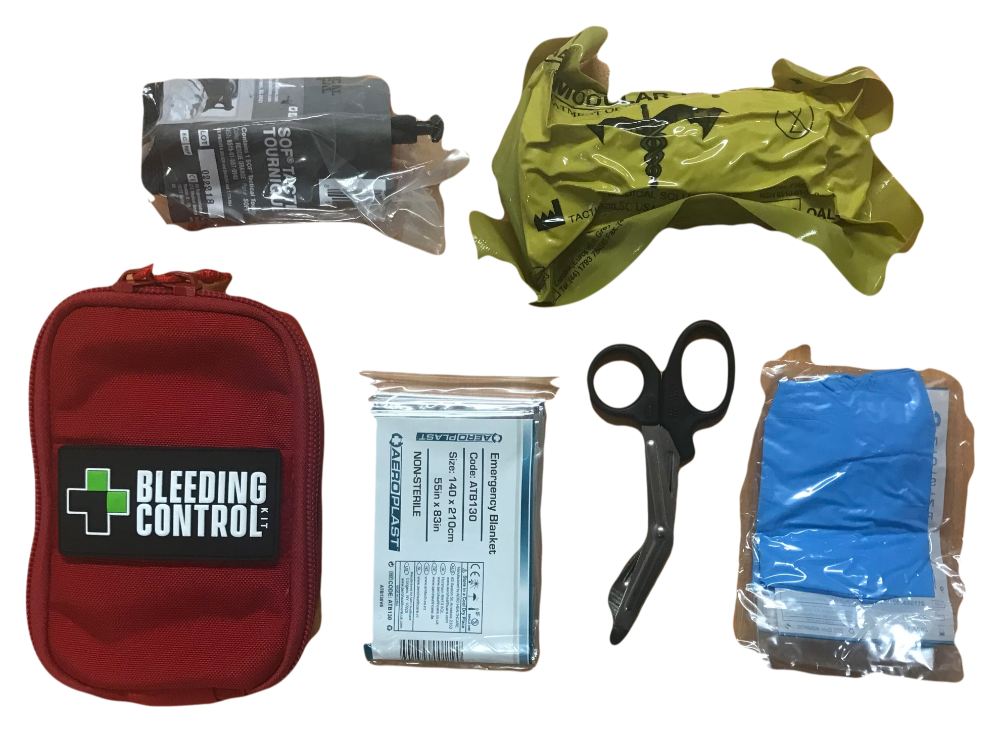 Kit components laid out: red pouch, tourniquet, emergency bandage, gloves, trauma shears, and chest seal.