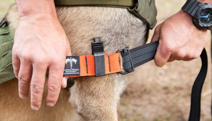 K9 Tourniquet being applied to a dog’s leg by a person wearing tactical gear.

