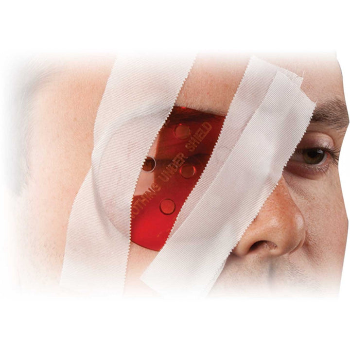 Polycarbonate eye shield in use, taped over a patient’s eye with white medical dressing.